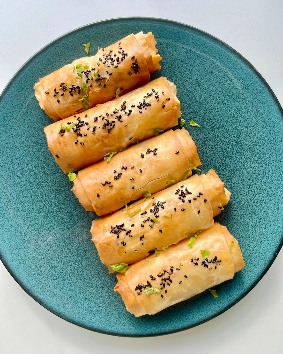 Golden crispy butter chicken rolls made with phyllo pastry, garnished with black sesame seeds and served with mango chutney
