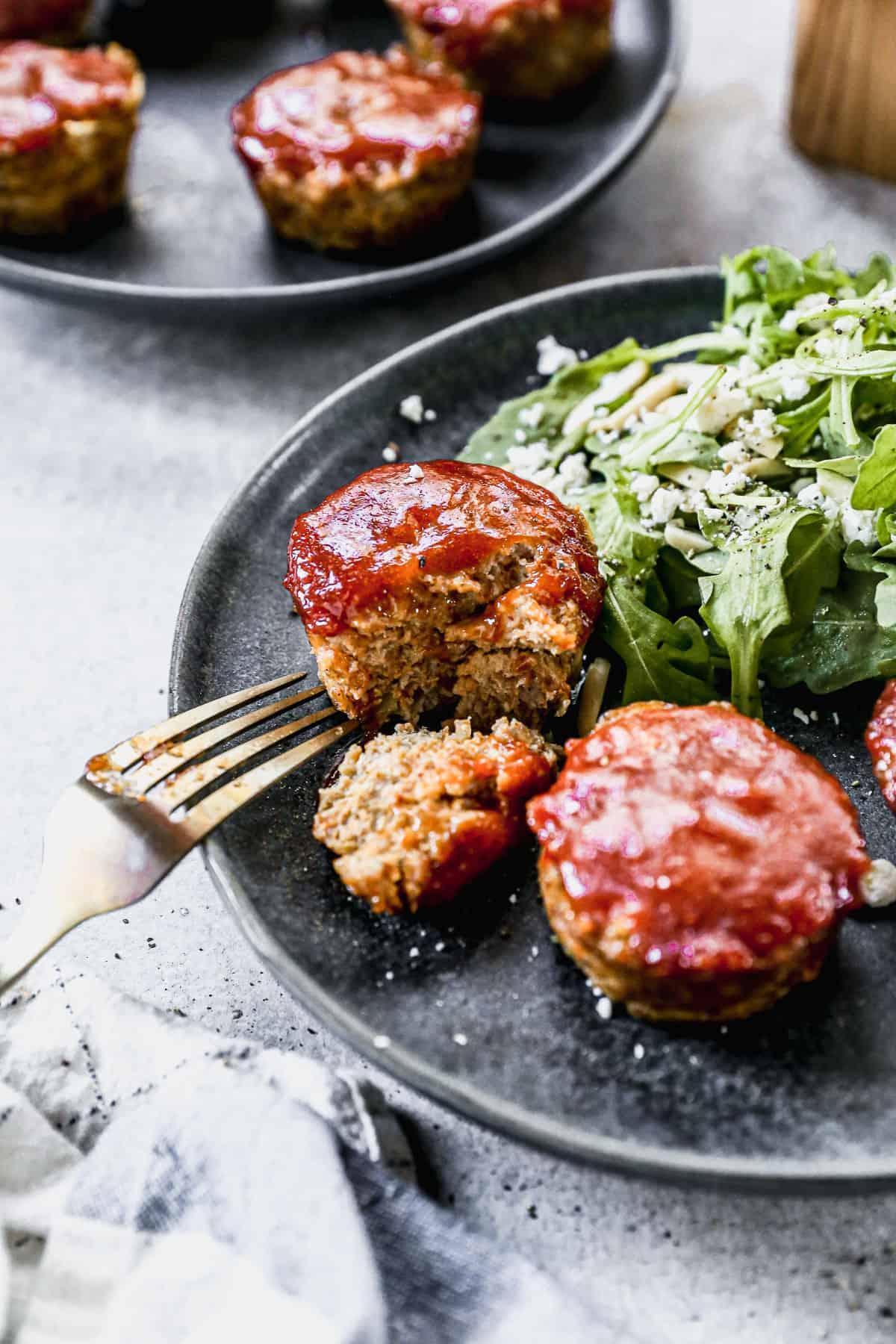 Golden brown mini meatloaves in muffin tin with glossy BBQ glaze, served alongside creamy mashed potatoes