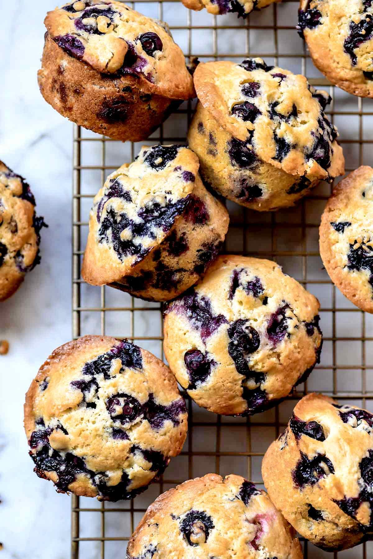 Golden-topped blueberry muffins with perfect dome shapes, filled with fresh blueberries, displayed on a rustic wooden board