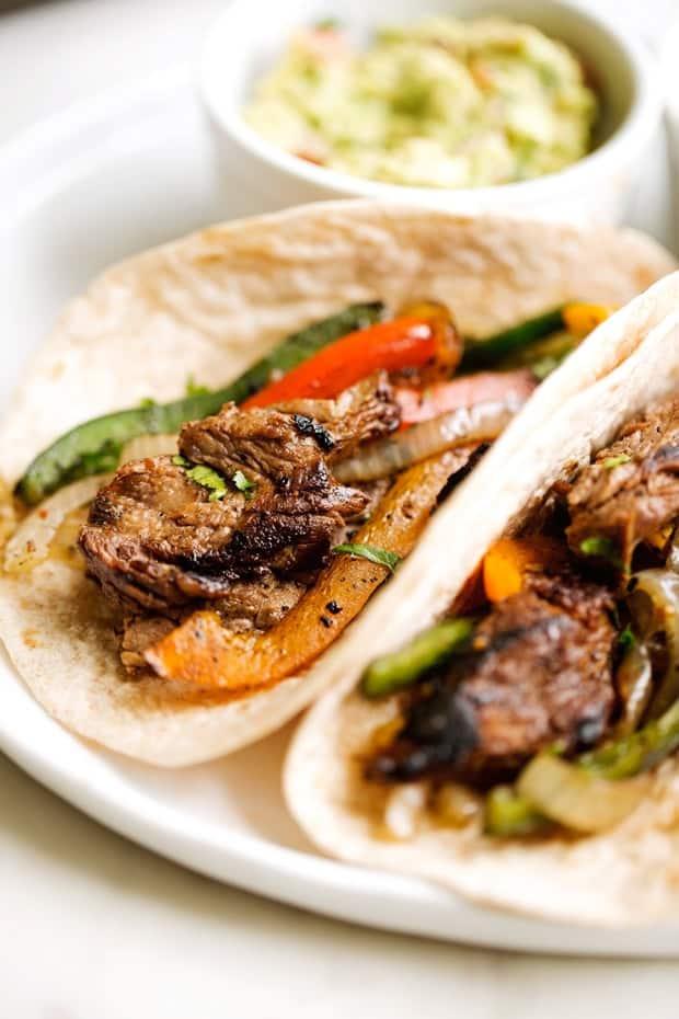 Sizzling steak fajitas with perfectly charred marinated beef strips, colorful bell peppers and onions in a cast iron skillet