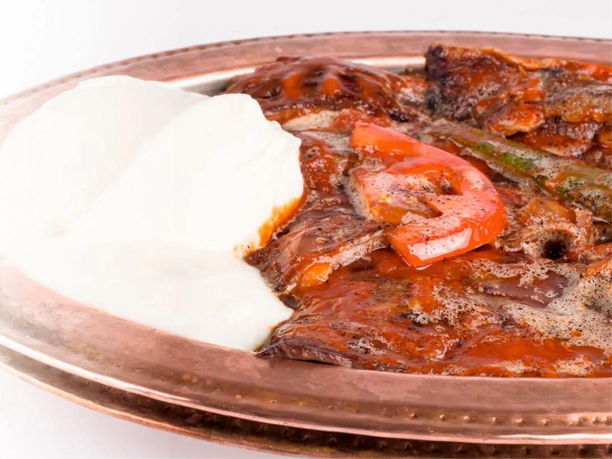 Authentic Turkish Iskender kebab with tender chicken, creamy yogurt, and golden buttery pita bread on a traditional ceramic plate