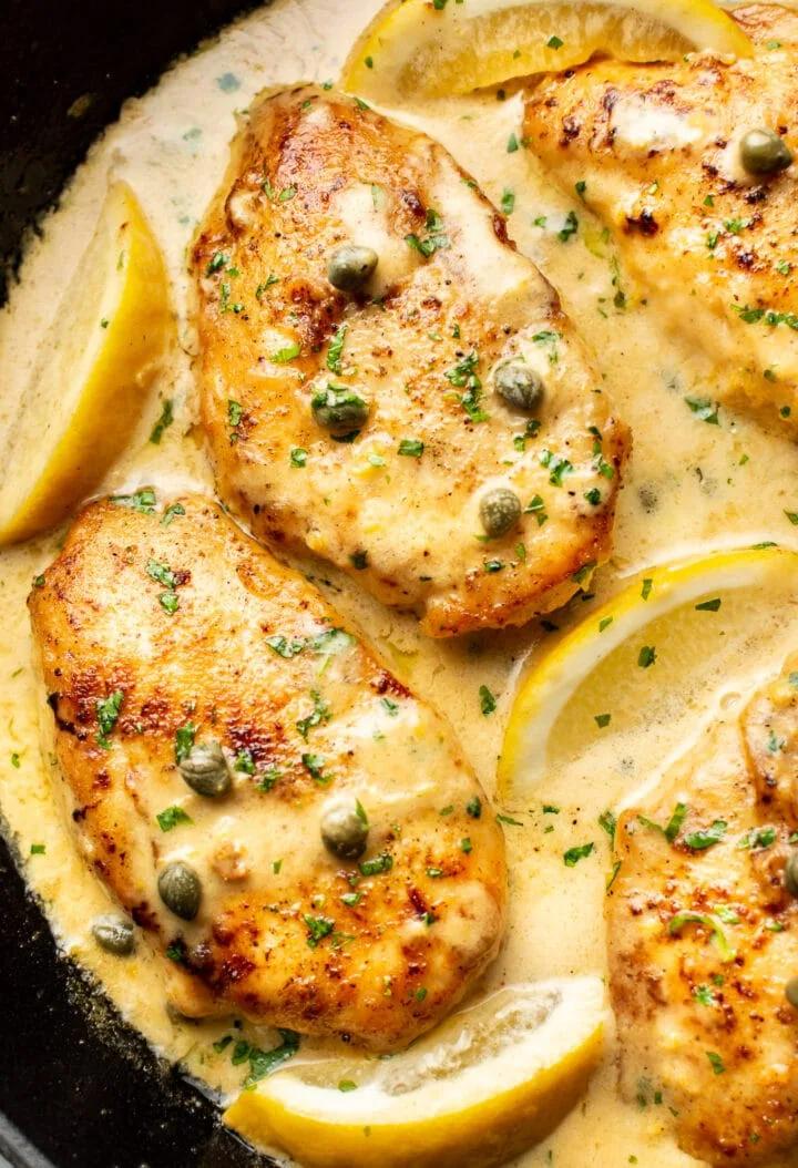 Golden chicken piccata with lemon caper sauce served on white plate with fresh parsley garnish