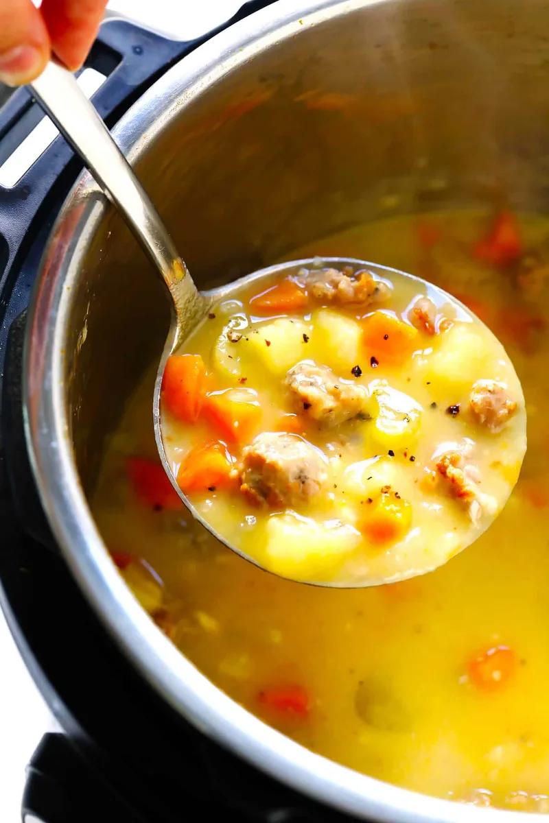 Bowl of creamy turkey cheeseburger soup topped with melted cheddar cheese and green scallions on a rustic wooden table