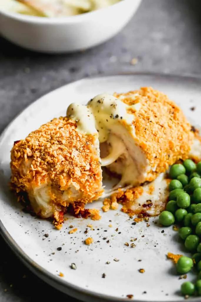 Golden crispy chicken cordon bleu sliced to show melted Swiss cheese and ham filling with mustard sauce