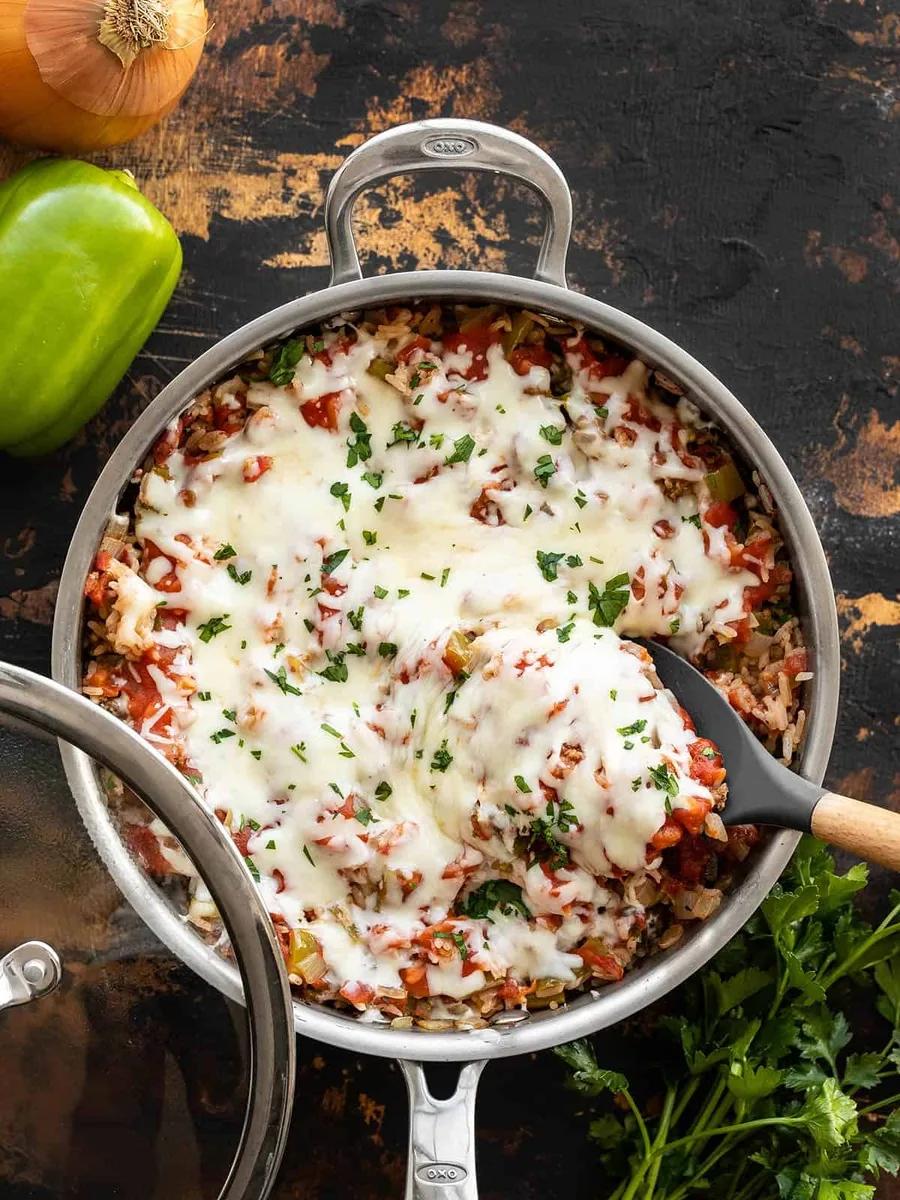 Unstuffed bell peppers in a cast iron skillet topped with melted mozzarella cheese and fresh herbs