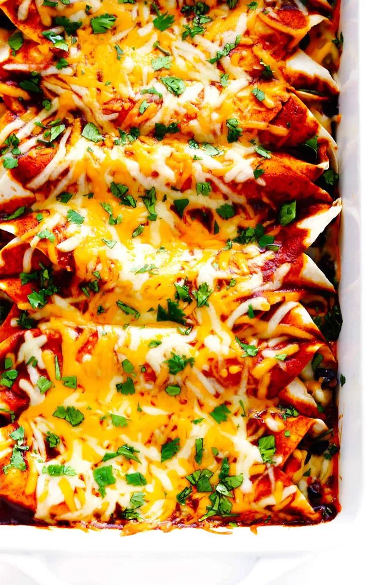 Golden baked chicken enchiladas topped with melted cheese and fresh cilantro in a white baking dish