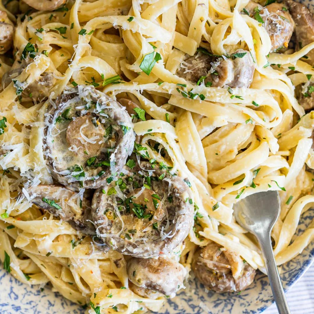 A bowl of creamy pasta with browned sliced mushrooms, lemon zest and fresh herbs