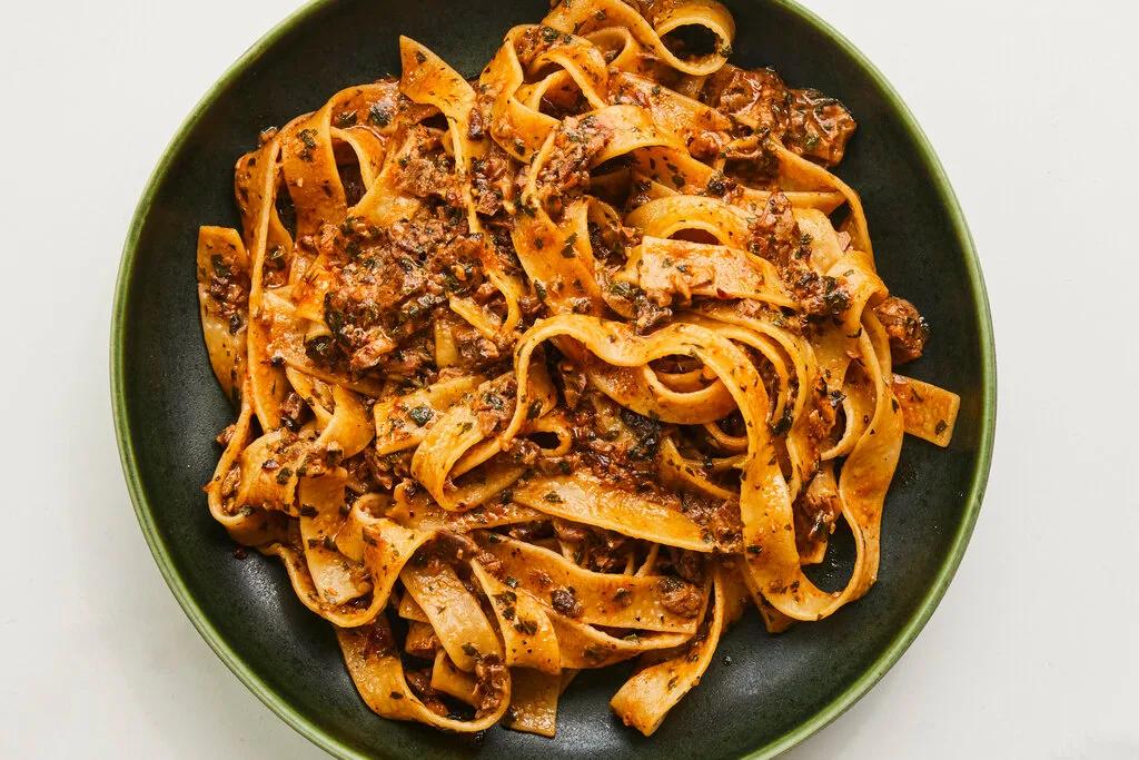 Creamy porcini mushroom ragù sauce coating fresh tagliatelle pasta with grated Parmesan cheese and fresh parsley garnish