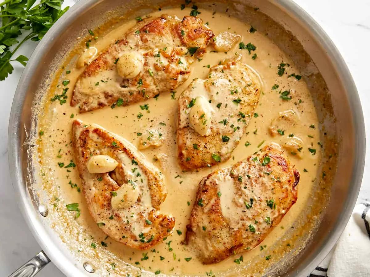 Creamy garlic chicken in a skillet with golden sauce and fresh parsley