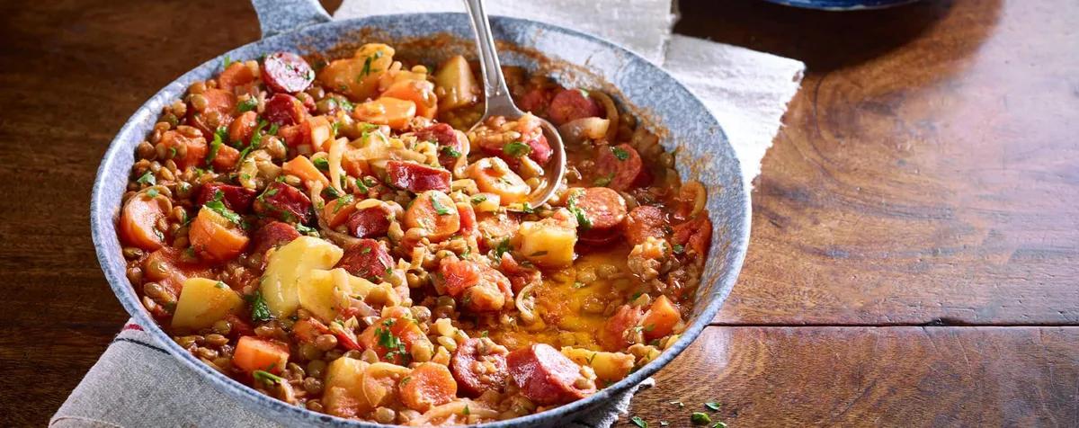 Bowl of chorizo and lentil stew with carrots, potatoes and parsley