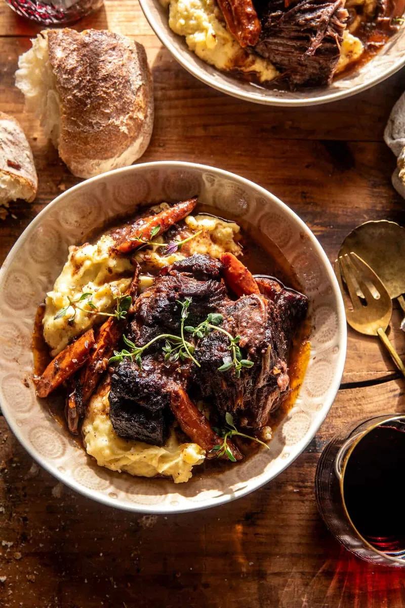 Sliced braised pot roast with carrots and gravy beside mashed potatoes