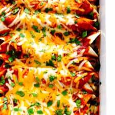 Golden baked chicken enchiladas topped with melted cheese and fresh cilantro in a white baking dish